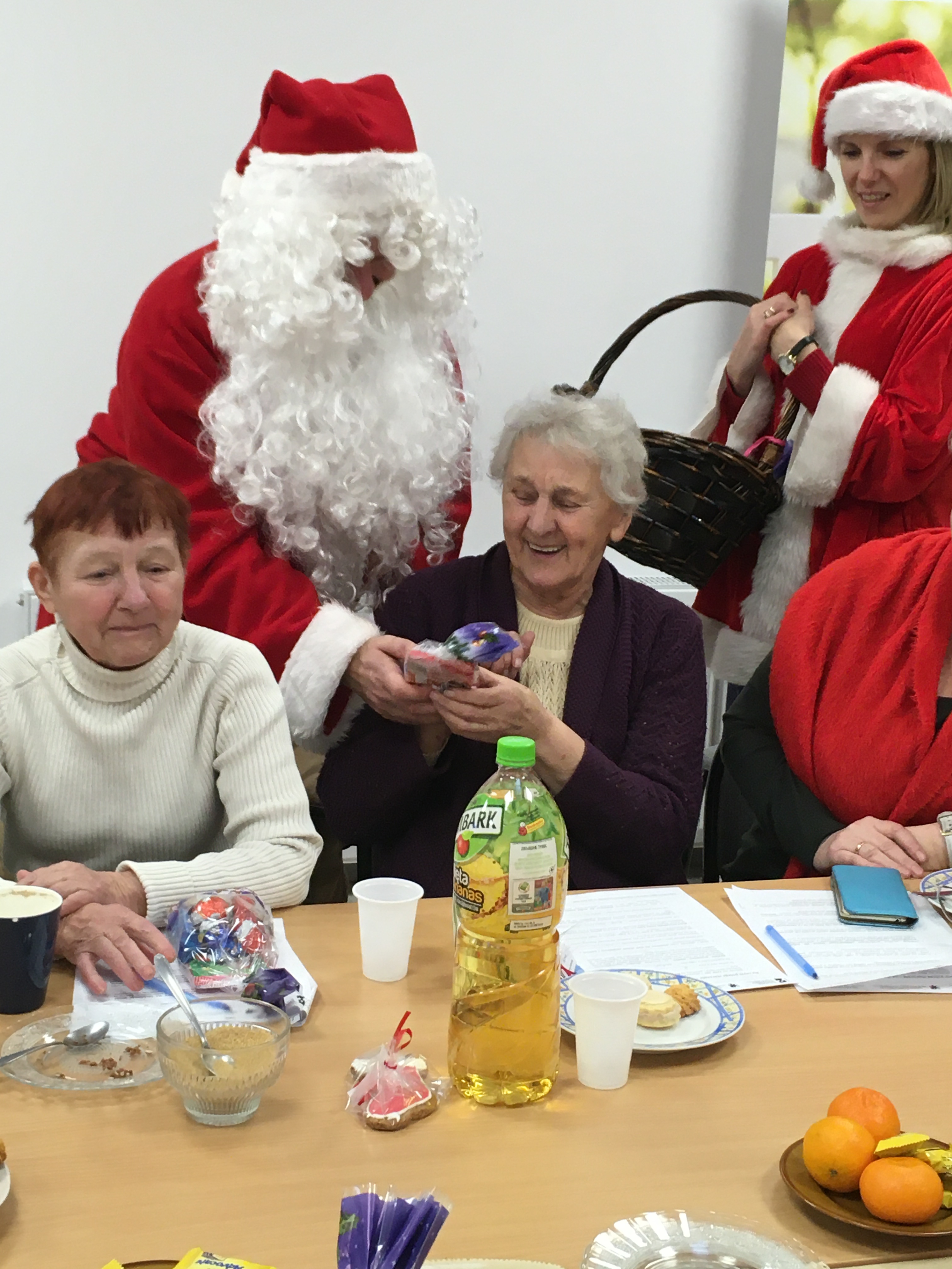 Święty Mikołaj wręczający słodycze jednej z seniorek.