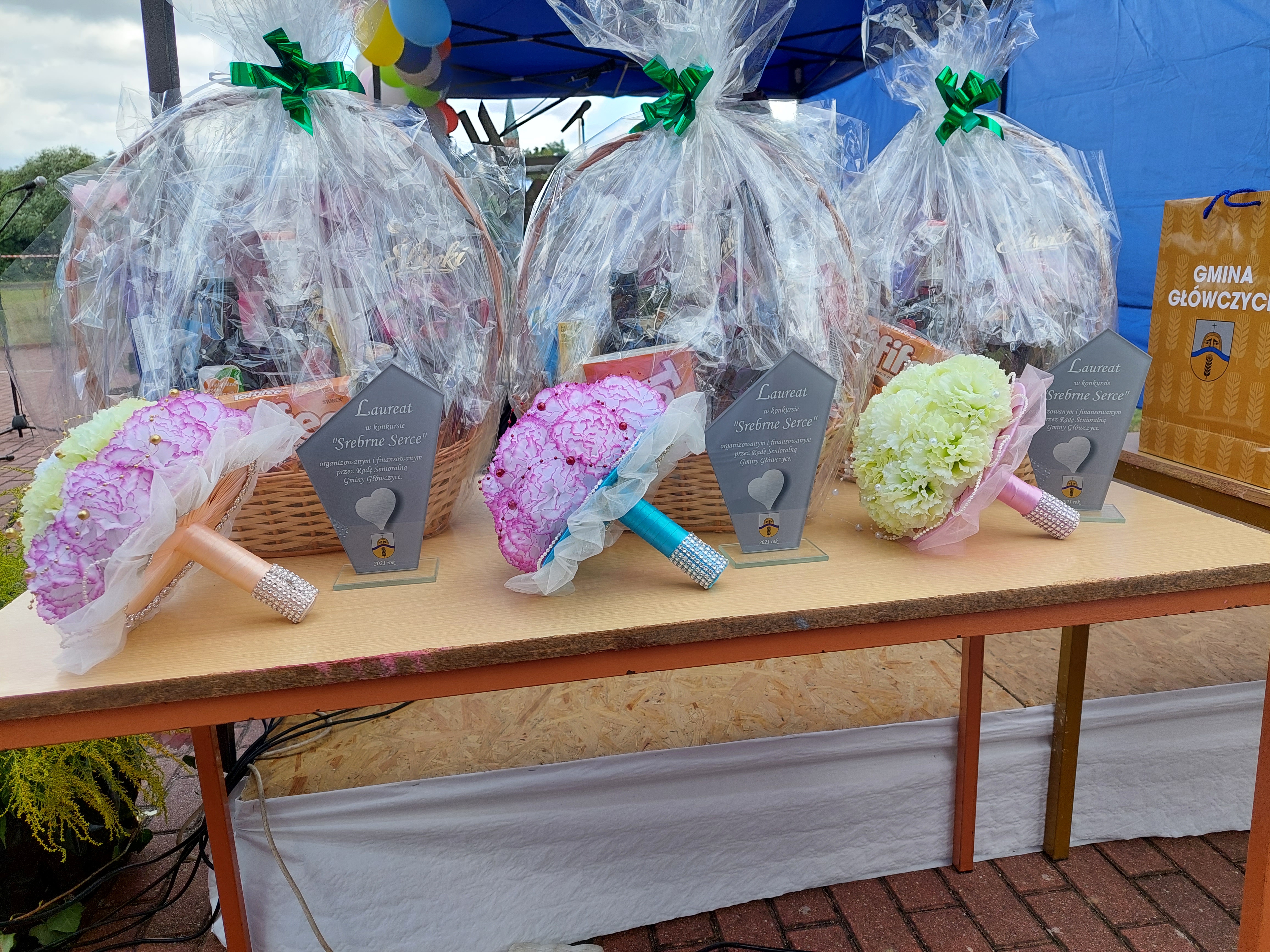 Słół z nagrodami rzeczowymi dla laureatów konkursu Srebrne Serce: kosze ze słodyczami, bukiety, statuetki.