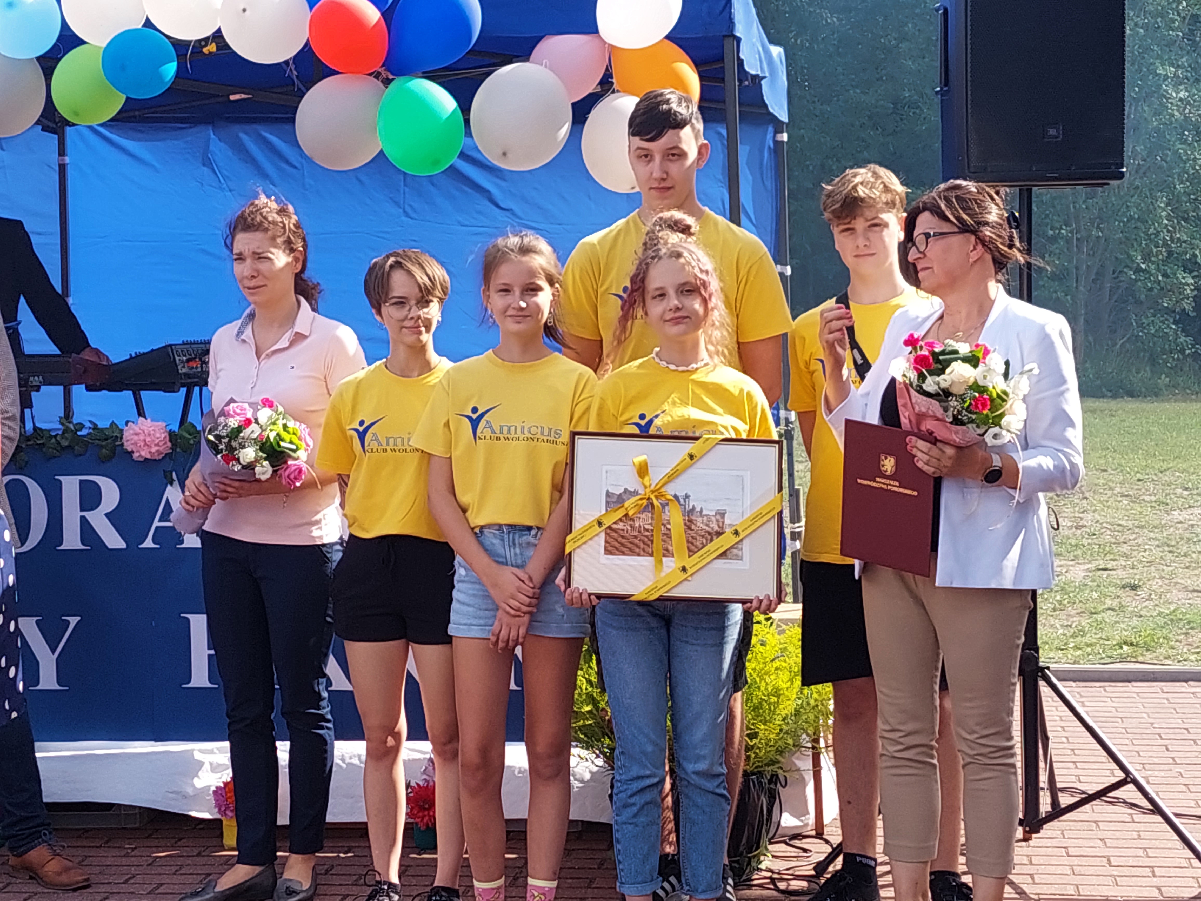 Wolontariusze klubu AMICUS z opiekunem pozujący do zdjęcia wraz z otrzymaną nagrodą od Marszałka Województwa Pomorskiego